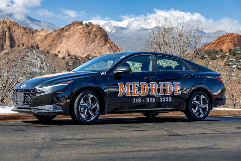 MedRide ambulatory medical transportation sedan parked in downtown Denver for statewide patient transport.