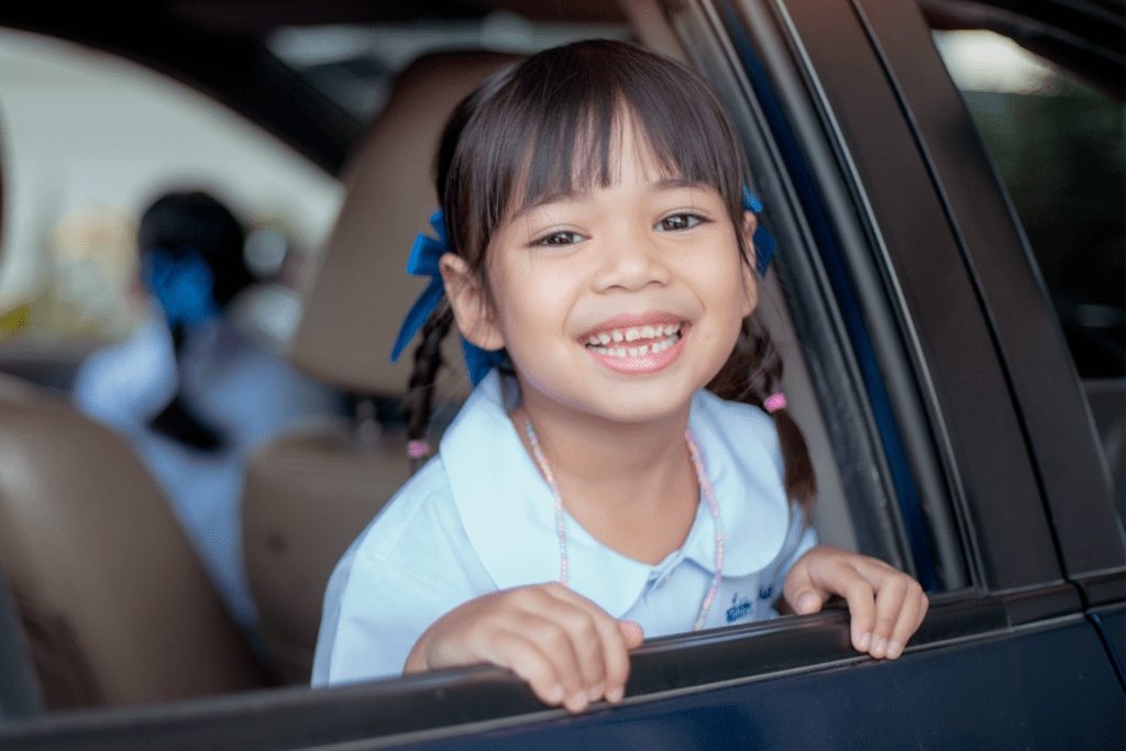 Young student smiling while seated safely inside a vehicle on the way to school transportation pickup