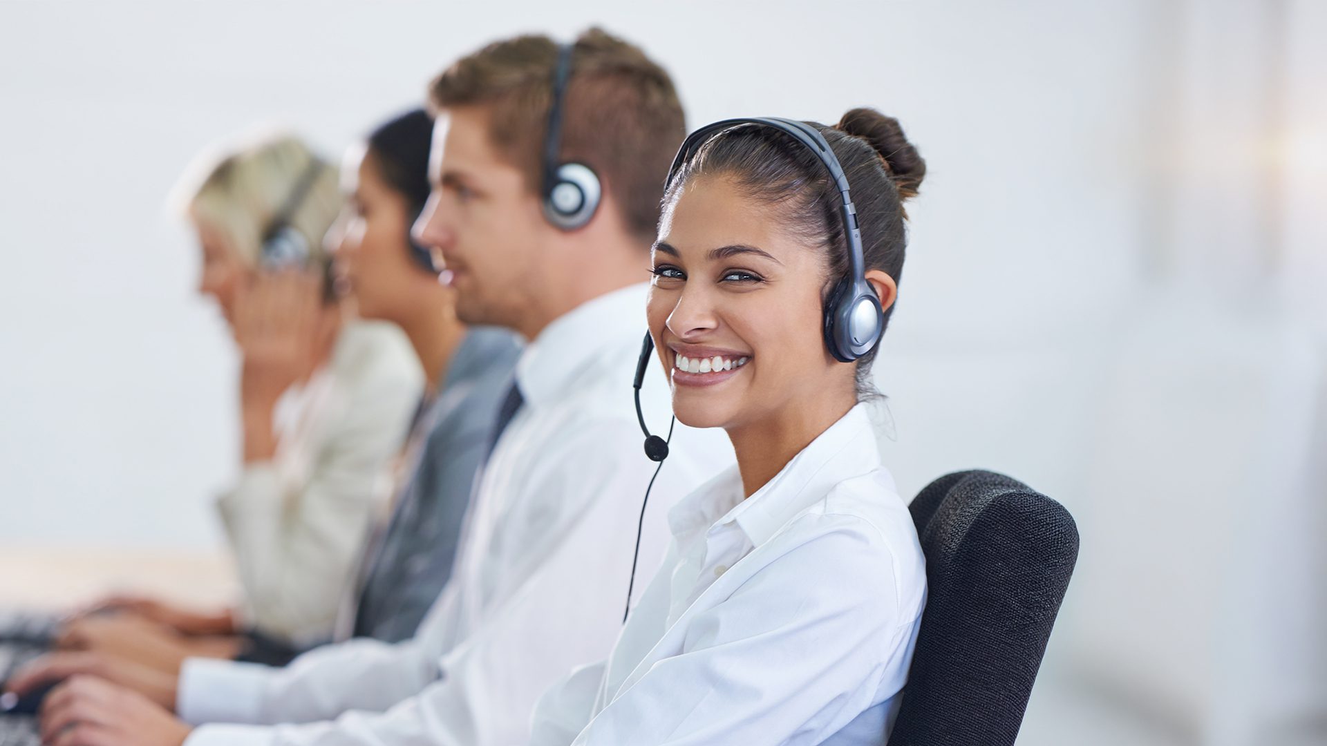 A smiling MedRide Colorado customer service representative wearing a headset in a call center setting.
