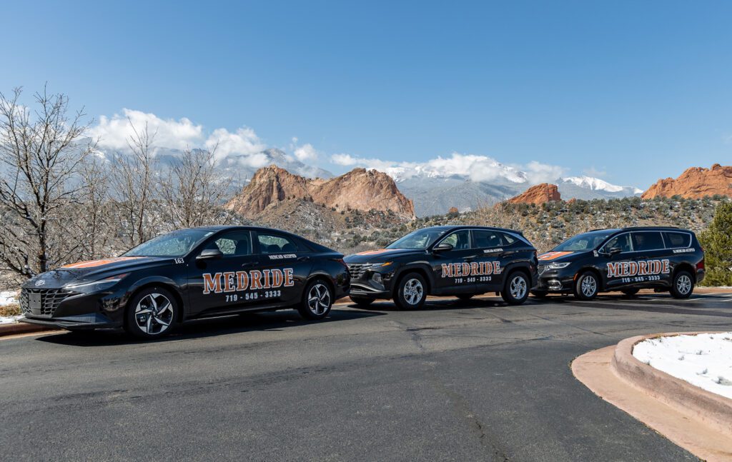 MedRide fleet of non-emergency medical transportation vehicles parked in front of Garden of the Gods in Colorado Springs.
